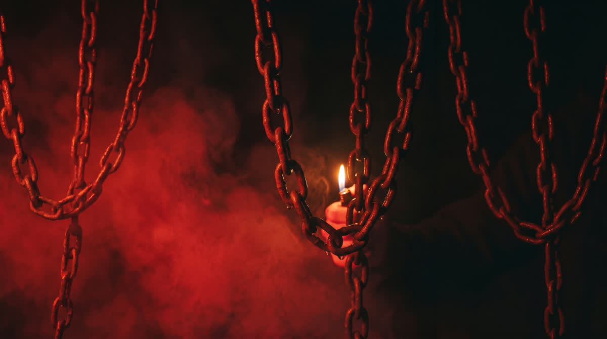 Schwere Metallketten im roten Nebel, dahinter eine einzelne Flamme
